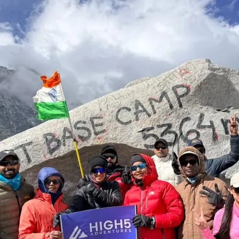 Trekkers holding a High 5 Adventures banner, with an Indian flag, in front of the painted 5,364 m boulder at Everest Base Camp, May 2026