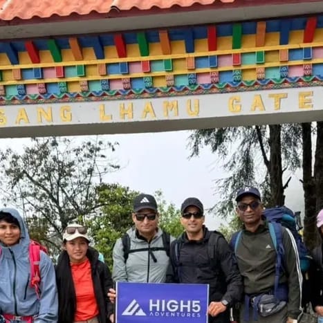 Trekkers holding a High 5 Adventures banner under the Pasang Lhamu Gate in Lukla, May 2026