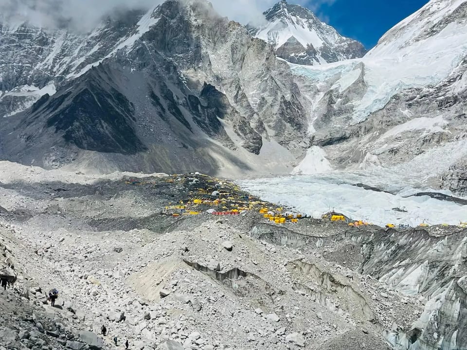 Who stays at Everest Base Camp: Everest Base Camp tents on the Khumbu Glacier. Yellow expedition tents below the icefall and trekkers on the rocky glacier trail, Everest Base Camp, Khumbu Glacier. Yellow expedition tents below the icefall and trekkers on the rocky glacier trail, Everest Base Camp, Khumbu Glacier